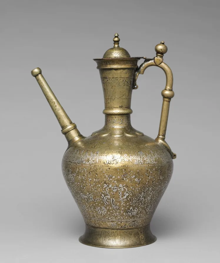 Bulbous brass ewer with lid, handle, long spout, and dense silver-inlaid ornament arranged in bands around the body.