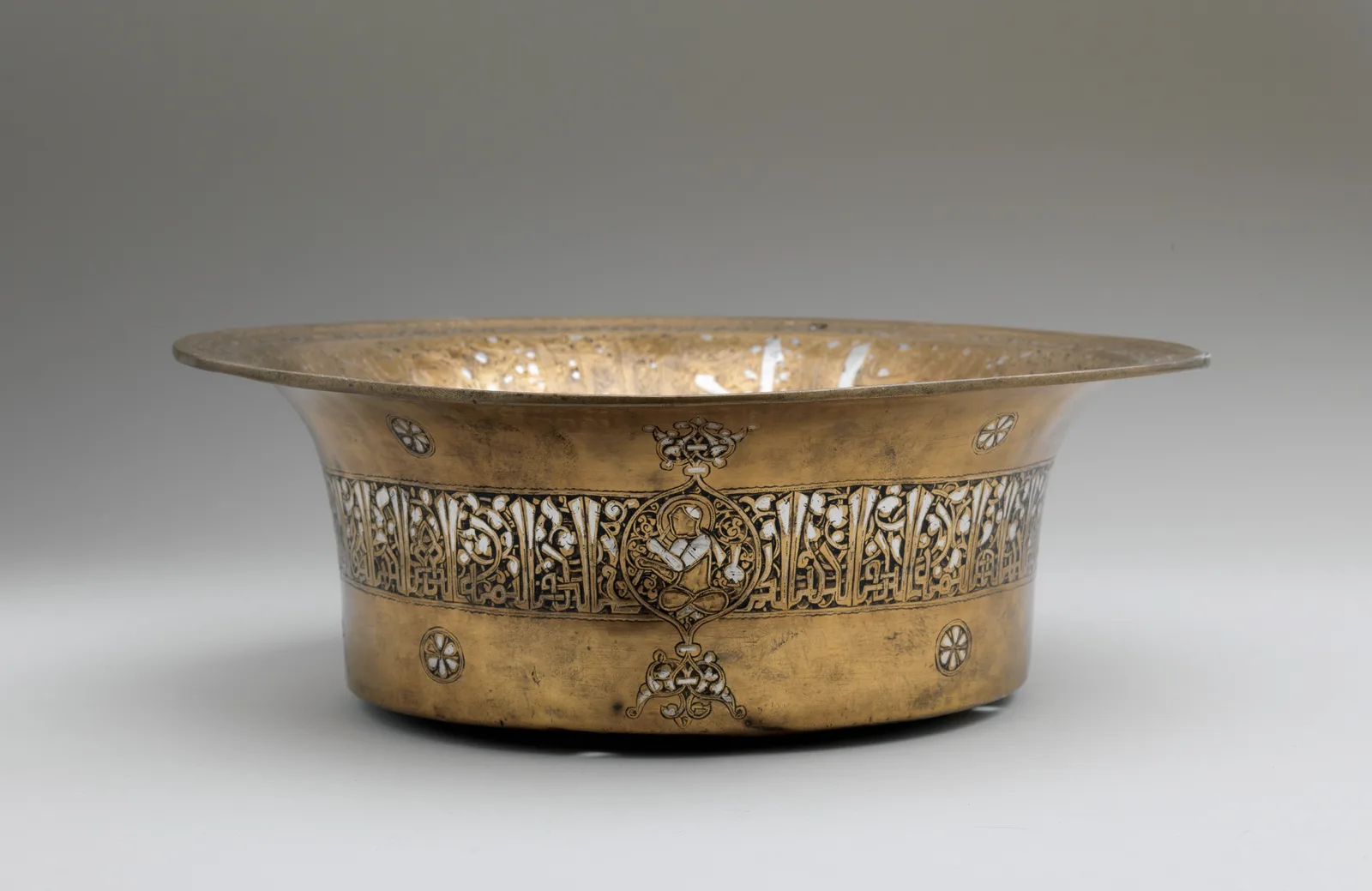 Low flaring brass basin with a band of silver-inlaid inscriptions, medallions, and dark ground around the exterior.